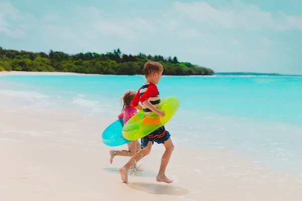 Glada barn- pojke och flicka- gå och bada på stranden Royaltyfria Stockfoton