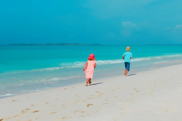 Glad pojke och flicka som springer på stranden Stockfoto
