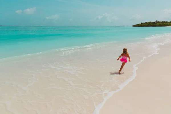 Glad liten flicka leka med vatten på stranden, familjesemester Royaltyfria Stockbilder