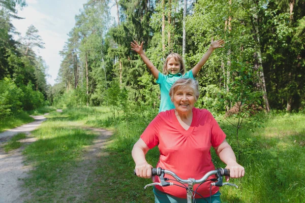 Gadis kecil yang bahagia dengan nenek naik sepeda di alam Stok Gambar