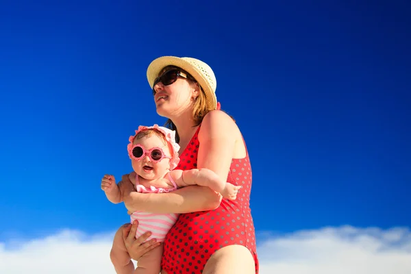 Moeder en baby op strand tegen blauwe hemel — Stockfoto