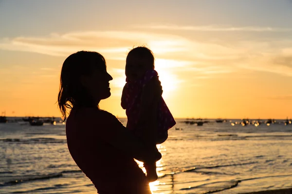 Mère heureuse et bébé s'amuser à la plage du coucher du soleil — Photo