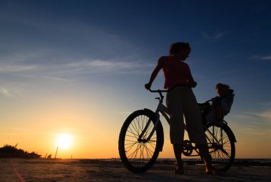 mother and baby biking at sunset clipart