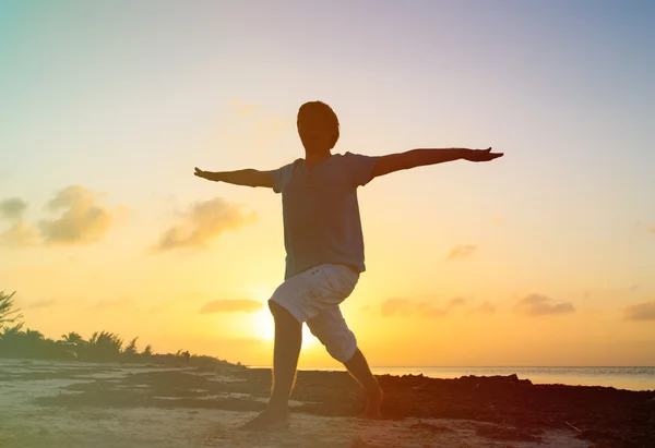 Silhouette of young man doing yoga at sunset — Stock Photo, Image