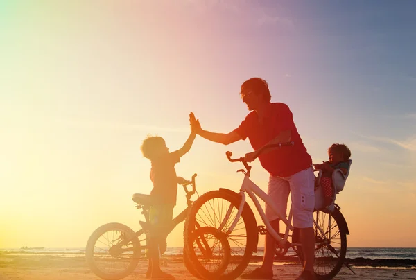 Pai com crianças de bicicleta ao pôr do sol — Fotografia de Stock