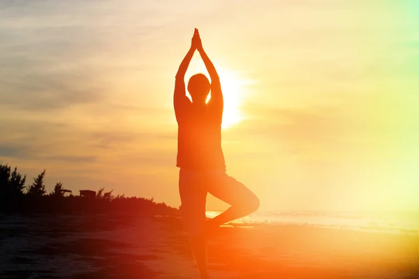 Silhouette of young man doing yoga at sunset — Stock Photo, Image