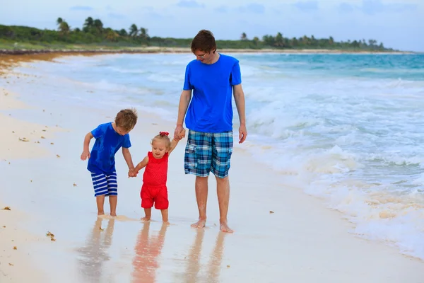 Vader en twee kinderen wandelen op het strand — Stockfoto