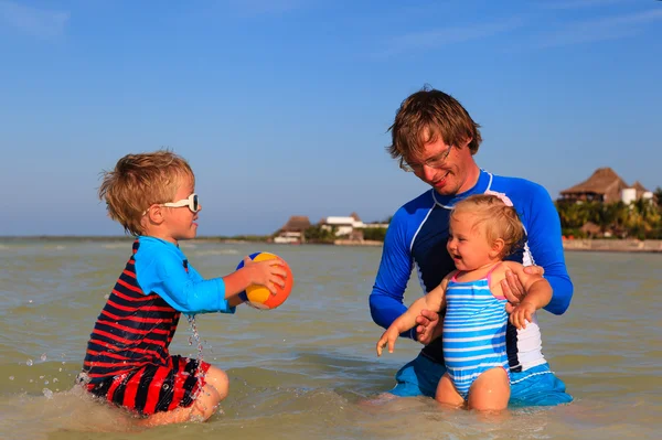 Vader en kinderen spelen bal op zee — Stockfoto