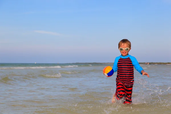 Маленький хлопчик грає м'яч на пляжі — стокове фото