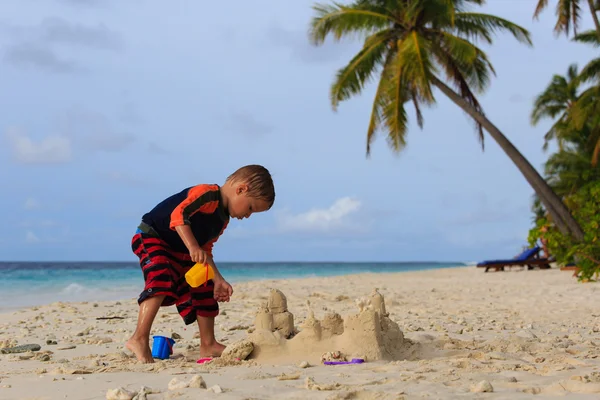 Malý chlapec písku hrad na tropické pláži — Stock fotografie