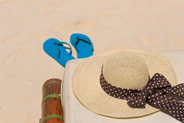 Hasır şapka ve kum plajı üzerinde flip flop