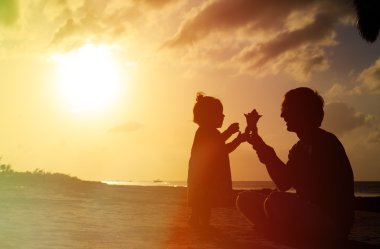 Baba ve küçük kızı siluetleri gün batımında