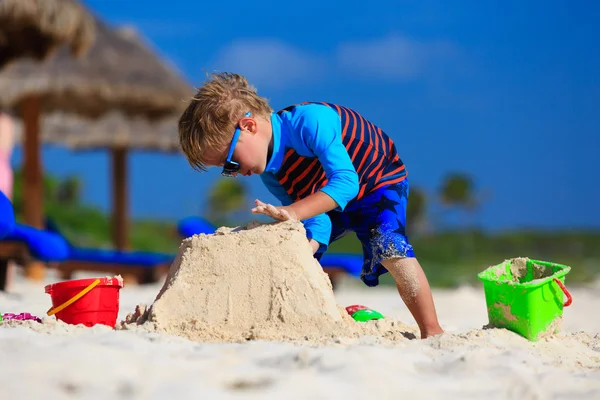 Menino edifício sandcastle na praia de verão — Fotografia de Stock