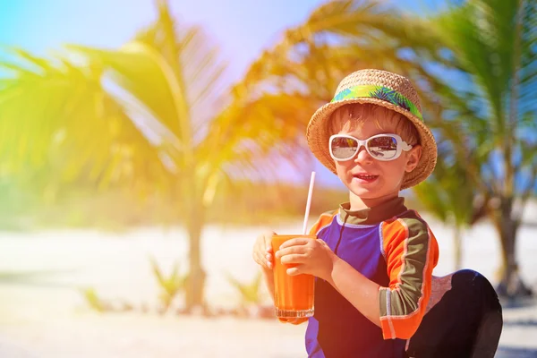 Bonito menino bebendo suco na praia tropical — Fotografia de Stock