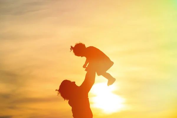 Pai e pequena filha silhuetas ao pôr do sol — Fotografia de Stock