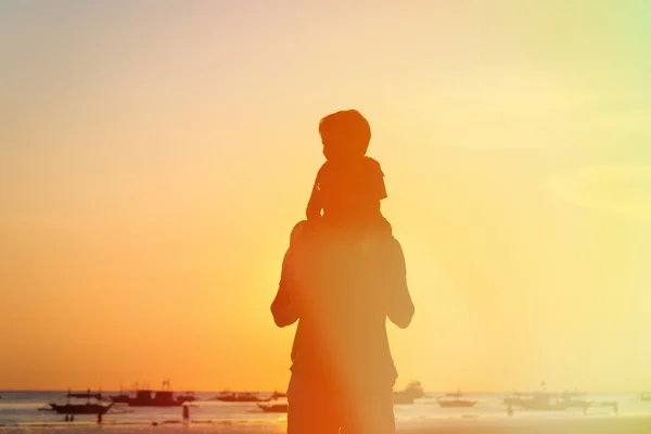 Pai e filho nos ombros olhando para o pôr do sol — Fotografia de Stock