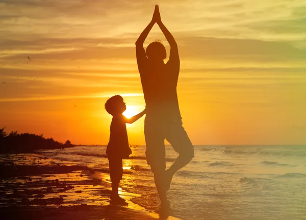 Far och son gör yoga vid solnedgången — Stockfoto