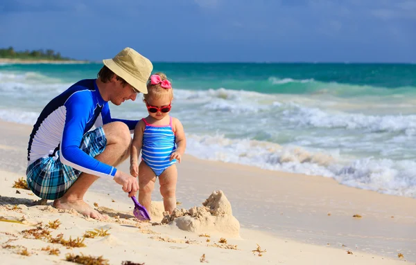 Padre e hija pequeña jugando con arena en la playa —  Fotos de Stock