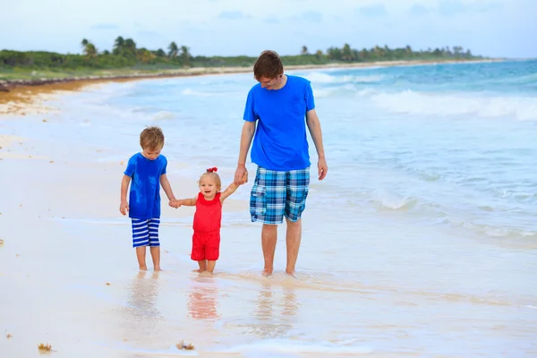Padre y dos niños caminando en la playa de verano — Foto de Stock