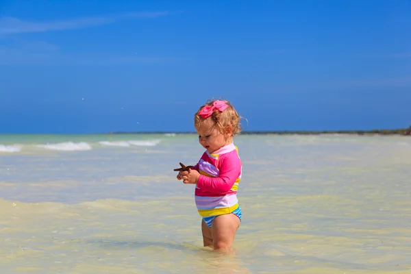Dziewczynka gospodarstwa rozgwiazdy w lato plaża — Zdjęcie stockowe