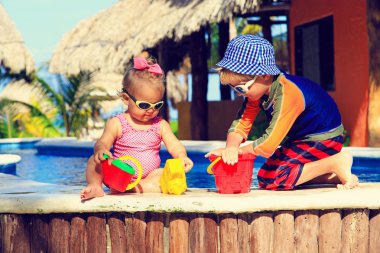 Yüzme havuzunda oynayan küçük çocuk ve yürümeye başlayan çocuk kız