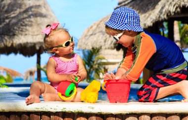 Yüzme havuzunda oynayan küçük çocuk ve yürümeye başlayan çocuk kız