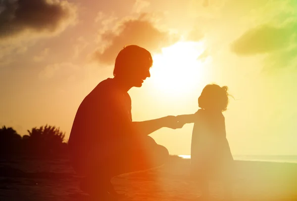 Siluetas de padre e hija pequeña al atardecer — Foto de Stock