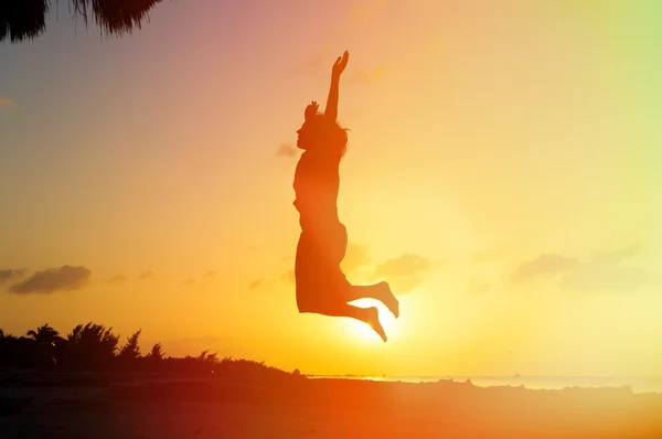 Silhueta de mulher pulando ao pôr do sol — Fotografia de Stock