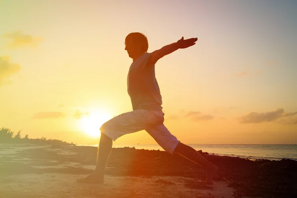 Silhouette of young man doing yoga at sunset — Stock Photo, Image