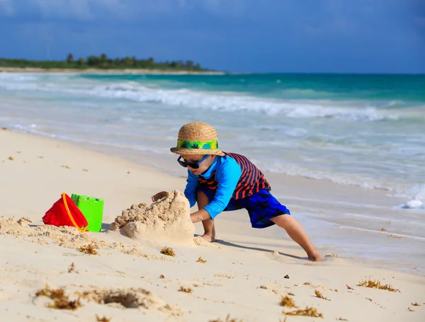Маленький мальчик строит песчаный замок на пляже — стоковое фото