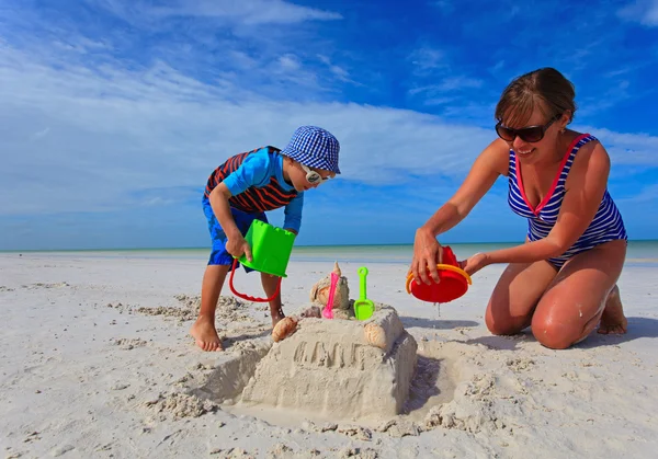 Mãe e filho construindo castelo de areia na praia de verão — Fotografia de Stock