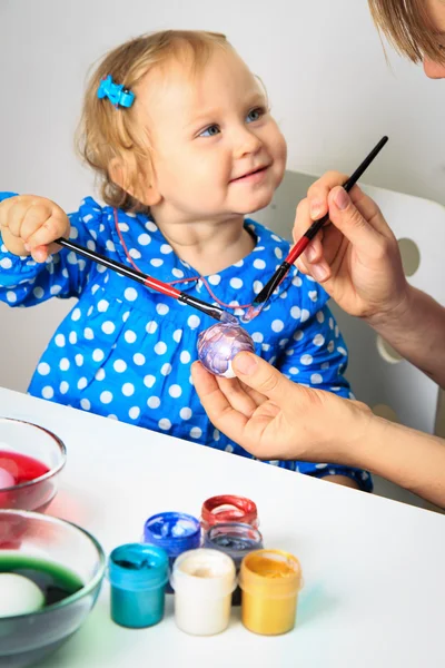 Mutter und kleine Tochter bemalen Ostereier lizenzfreie Stockbilder