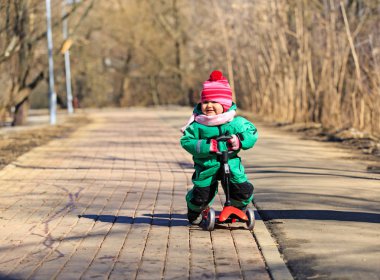 mutlu küçük kız scooter binmek için öğrenme