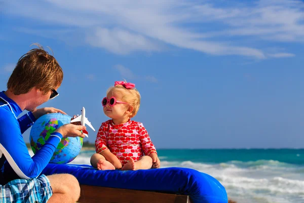 Vader en kleine dochter spelen met globe op het strand — Stockfoto