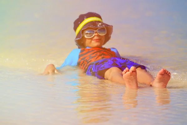 little boy playing with water on summer beach