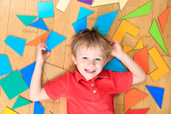 Bambino felice con puzzle giocattoli sul pavimento in legno — Foto Stock