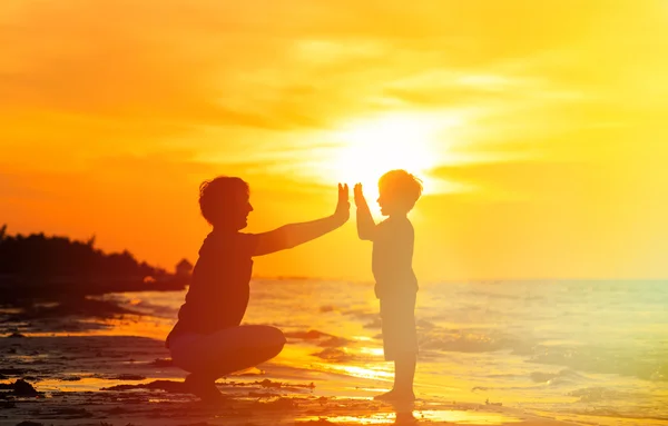 Far och son spelar på sunset havet — Stockfoto
