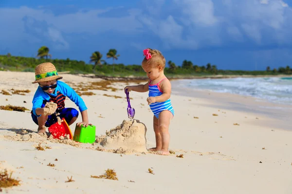 Kleine jongen en peuter meisje spelen met zand op het strand — Stockfoto