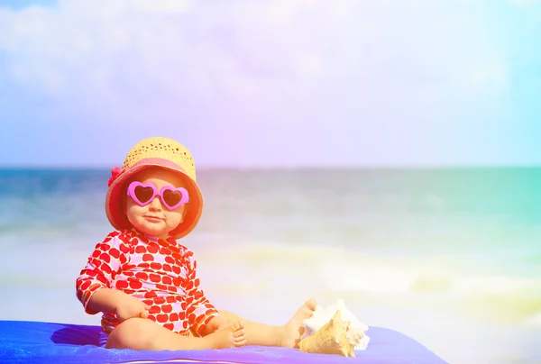 Schattig klein meisje met schelpen op het strand — Stockfoto