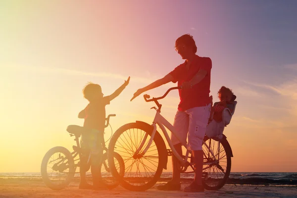 Padre con dos hijos en bicicleta al atardecer — Foto de Stock
