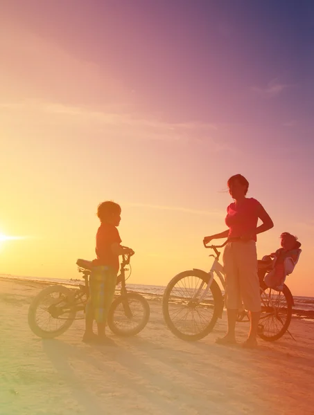 Moeder met kinderen fietsen bij zonsondergang — Stockfoto