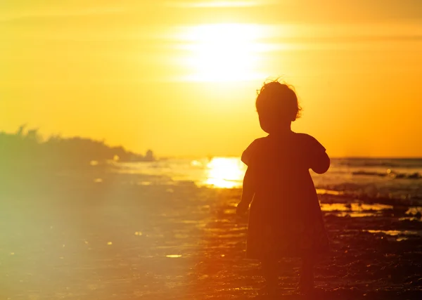 Liten flicka gå på sunset beach — Stockfoto