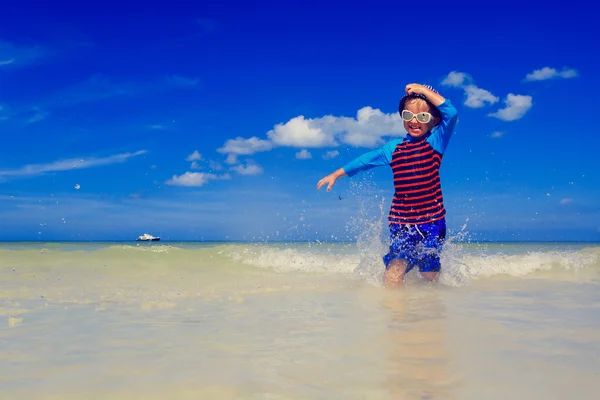열 대 해변에 물이 튀는 어린 소년 — 스톡 사진