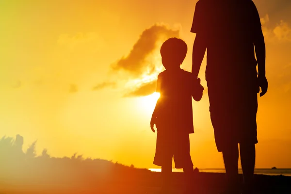 Père et fils tenant la main au coucher du soleil mer — Photo