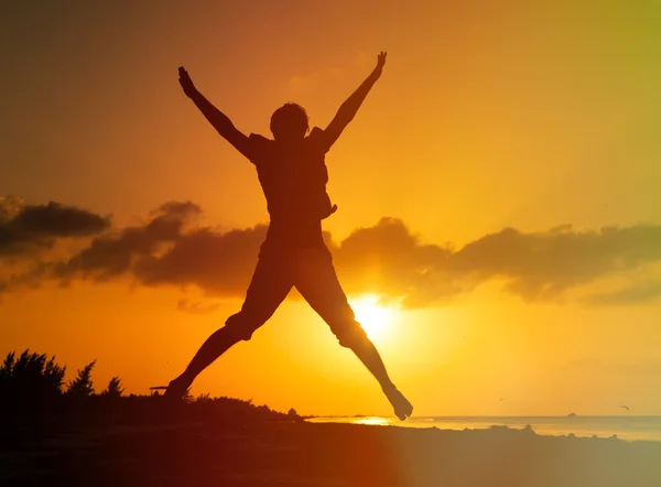 Happy man jumping on sunset beach — Stock Photo, Image