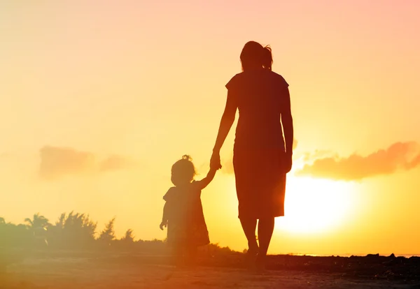 Moeder en kleine dochter lopen bij zonsondergang — Stockfoto