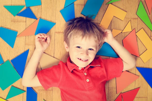 Glad liten pojke med pussel leksaker på trägolv — Stockfoto