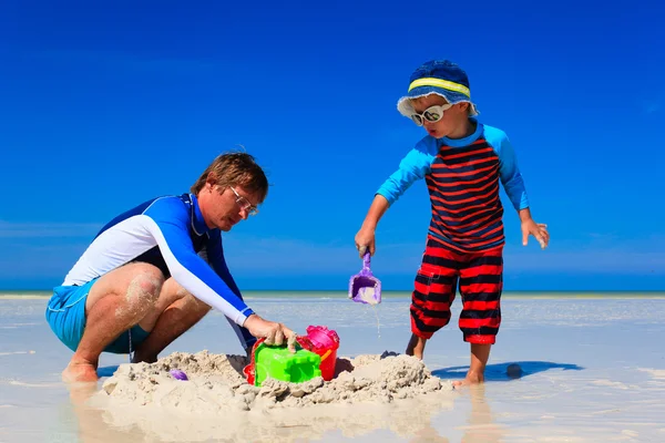 Отец и сын строят замок из песка на пляже — стоковое фото