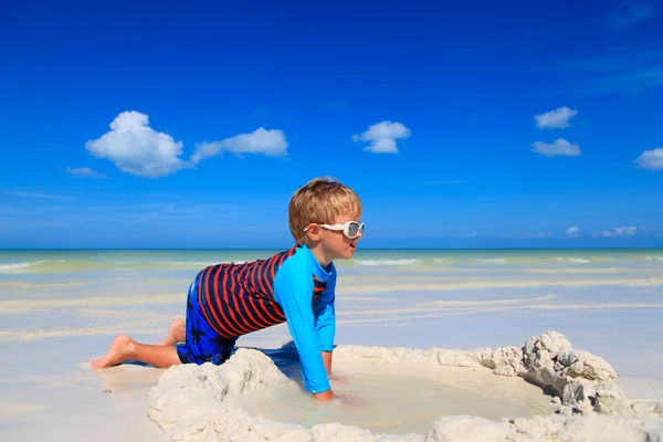 Маленький мальчик играет с песком на летнем пляже — стоковое фото