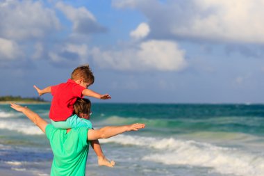 Mutlu baba ve oğul kumsalda oynuyor.
